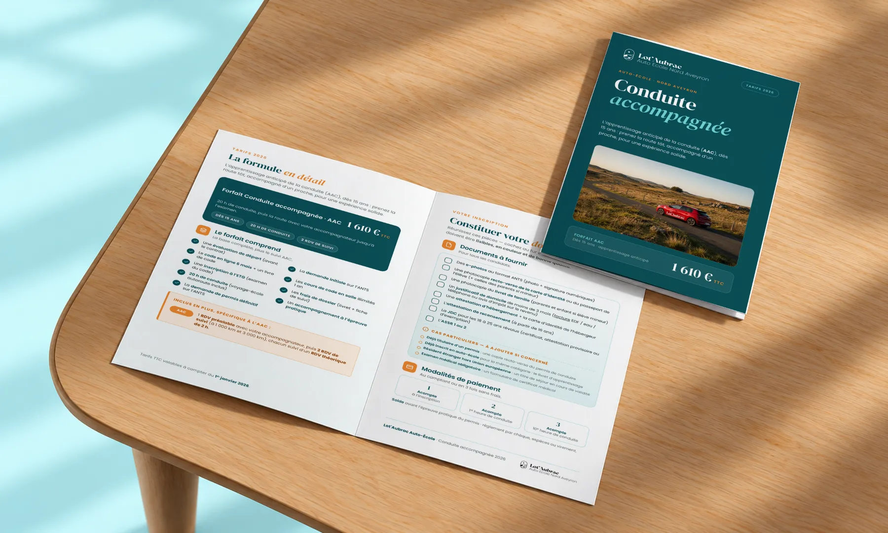 Flyer dépliant de l'auto-école Lot'Aubrac pour la conduite accompagnée (AAC) : couverture vert minuit et pages intérieures posés sur une table en bois